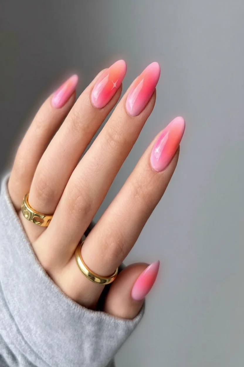 Mano con uñas alargadas en forma almendrada, efecto jelly degradado rosa con acabado cristalino brillante