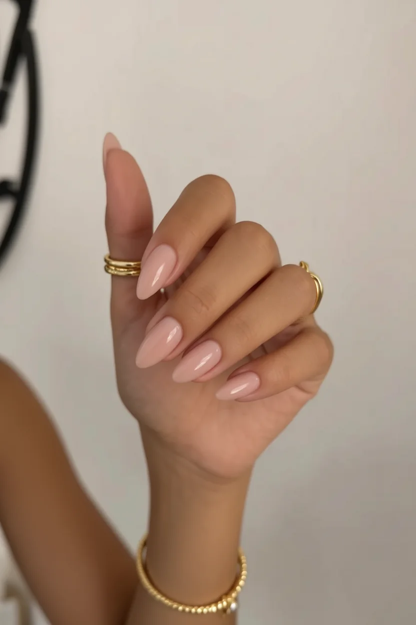 Mano con uñas largas forma almendra pintadas en nude brillante