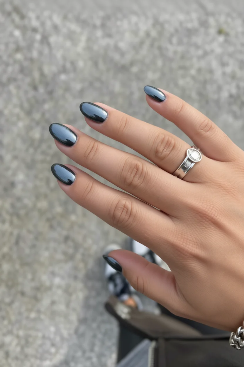 Mano con uñas negras chrome en forma ovalada y brillo especular