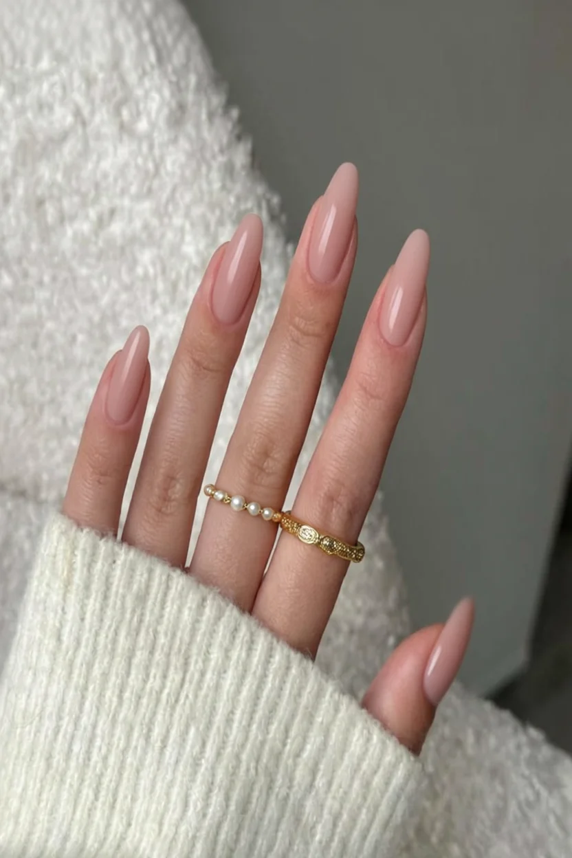 Mano con uñas almendradas largas y brillantes en tono nude