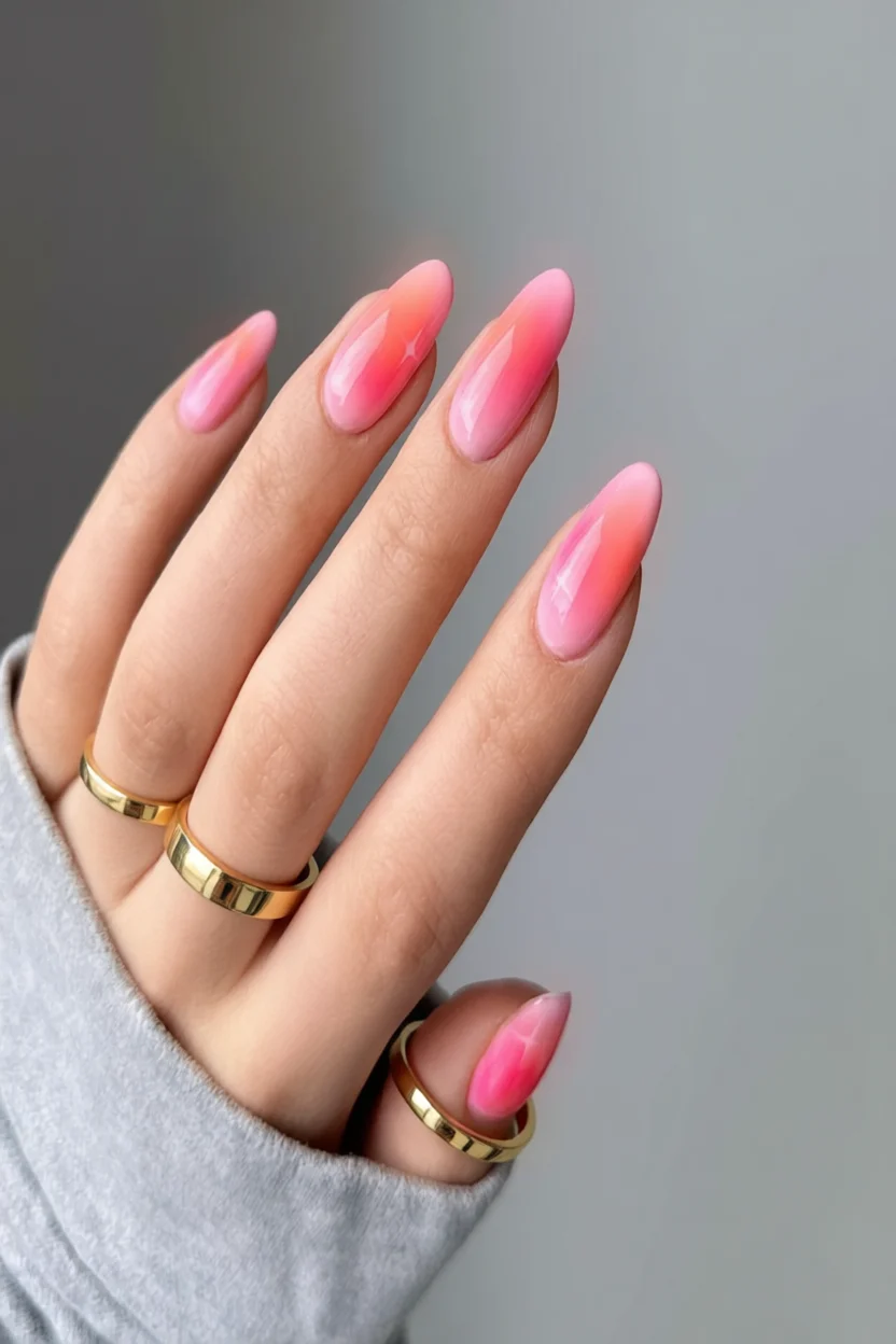 Uñas largas forma almendrada con diseño degradado en tonos rosa y anillos dorados