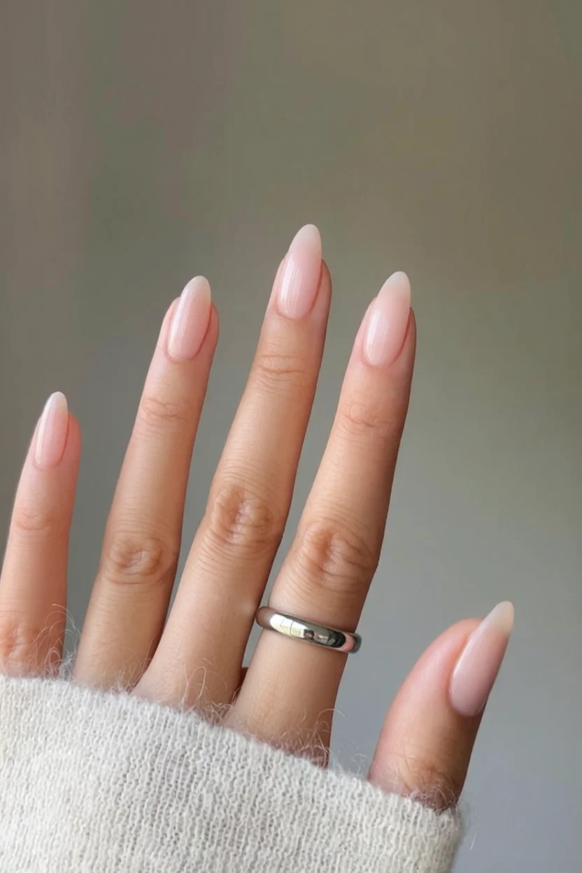 Mano con uñas almendradas en tono nude translúcido brillante