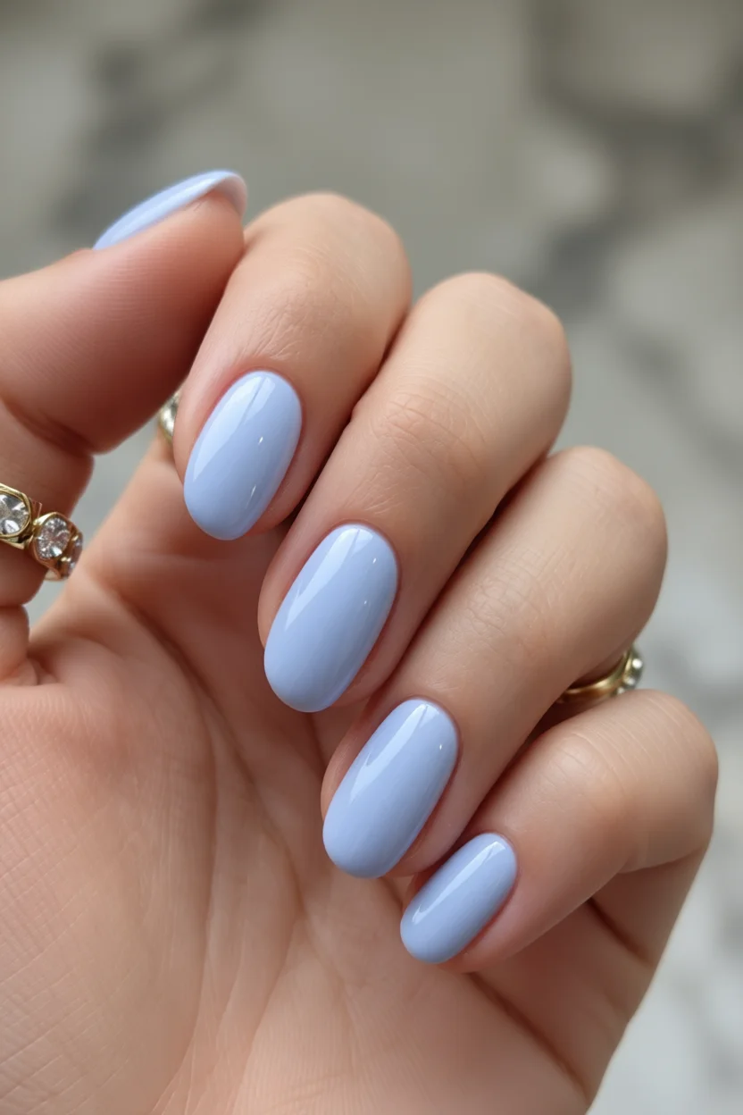 Mano con uñas ovaladas pintadas de azul pastel brillante y corte clásico