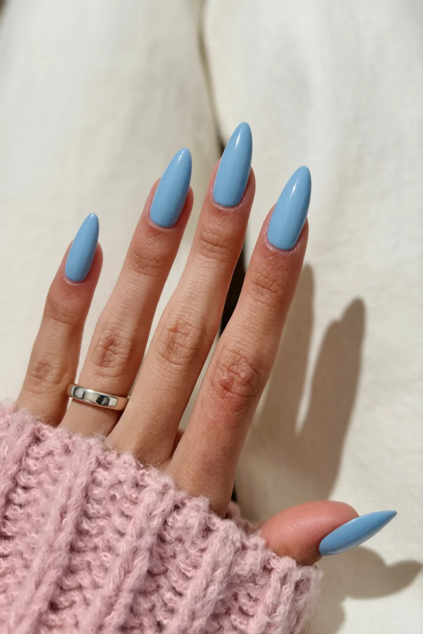 Mano con uñas largas ovaladas pintadas de azul pastel brillante