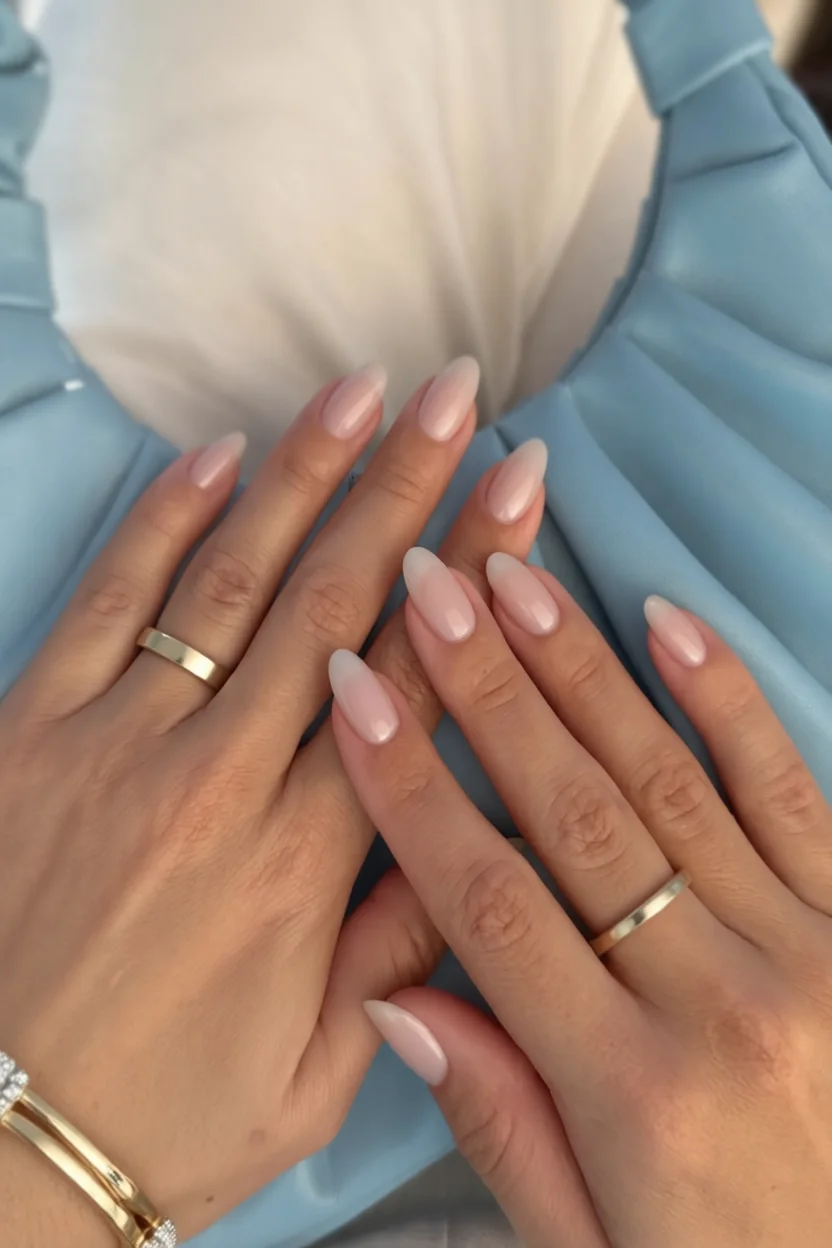 Manos con uñas almendradas en tono rosa lechoso con efecto perla y brillo satinado