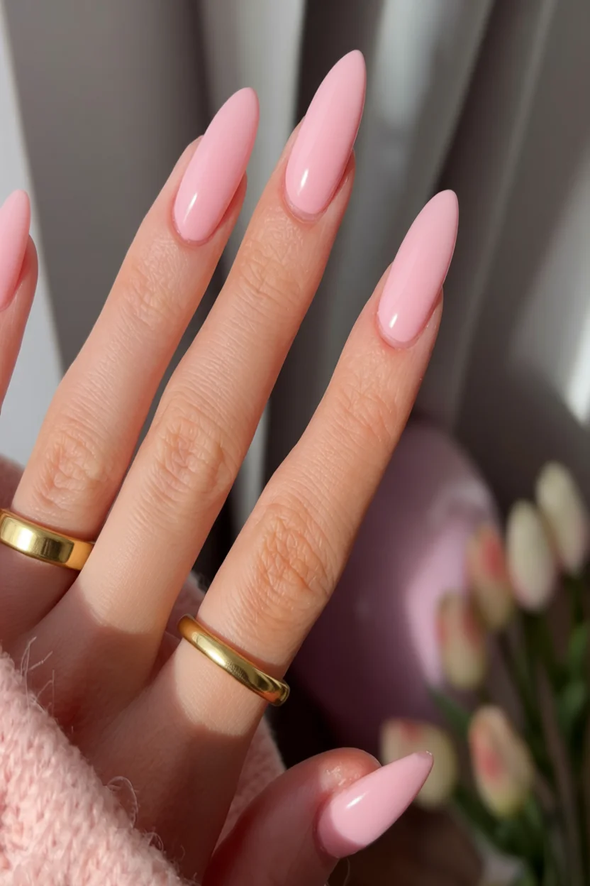 Mano con uñas largas ovaladas en tono rosa pastel brillante