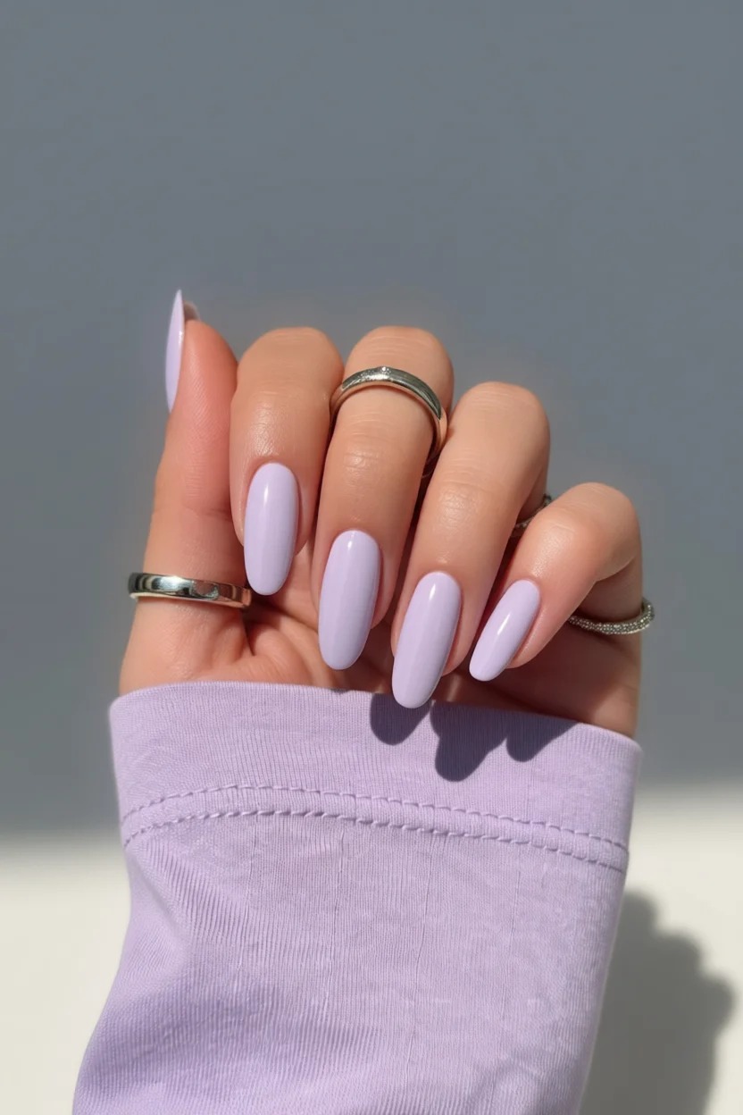 Mano con uñas ovales largas pintadas de color lavanda brillante con acabado glossy