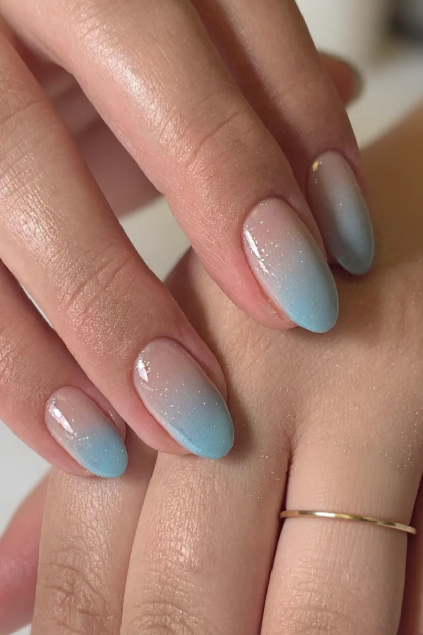 Uñas ovaladas con efecto degradado de nude a azul claro y brillo suave