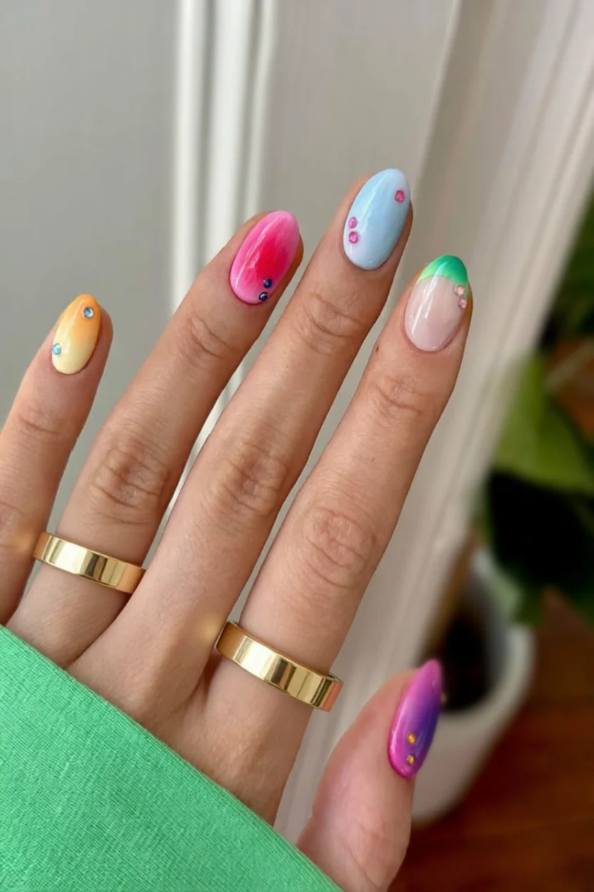Uñas ovaladas con efecto aura multicolor y detalles de purpurina y cristales