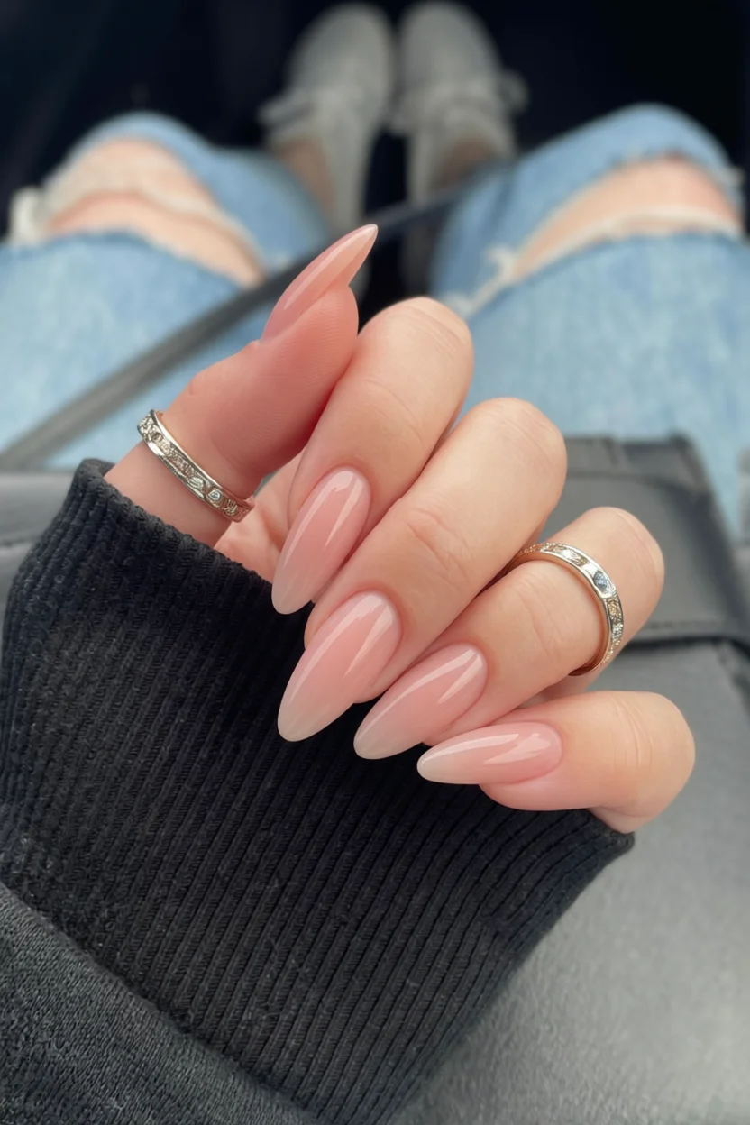 Mano con uñas largas en forma de almendra con degradado rosa suave y brillo glossy