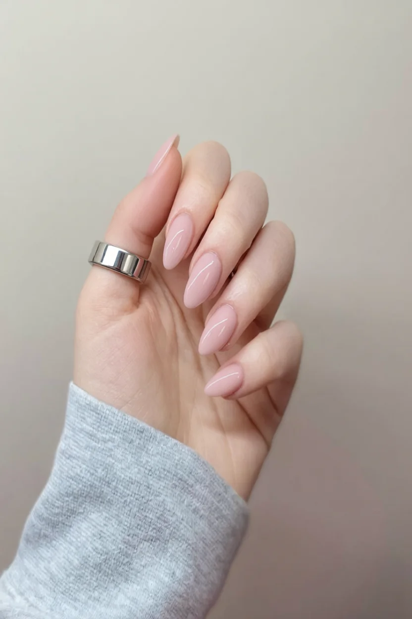 Mano con uñas almendradas en esmalte rosa pastel brillante