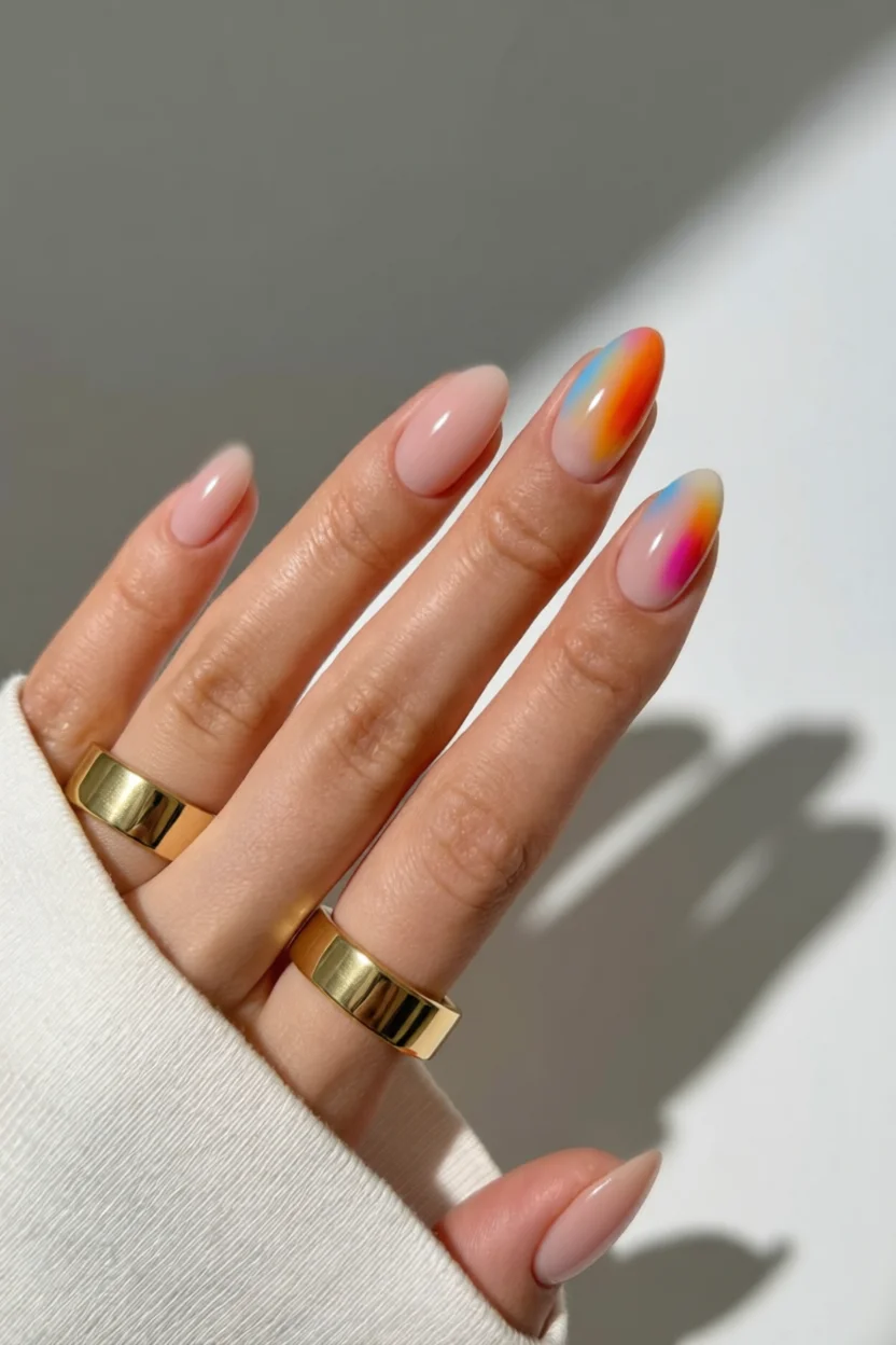 Uñas ovaladas con base nude rosada y puntas con degradado arcoíris