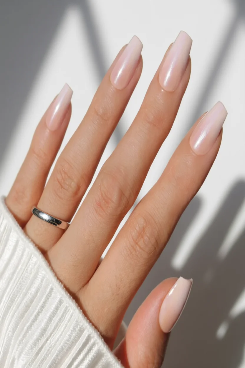 Mano con uñas largas forma almendra en color nude rosado con brillo perlatado suave