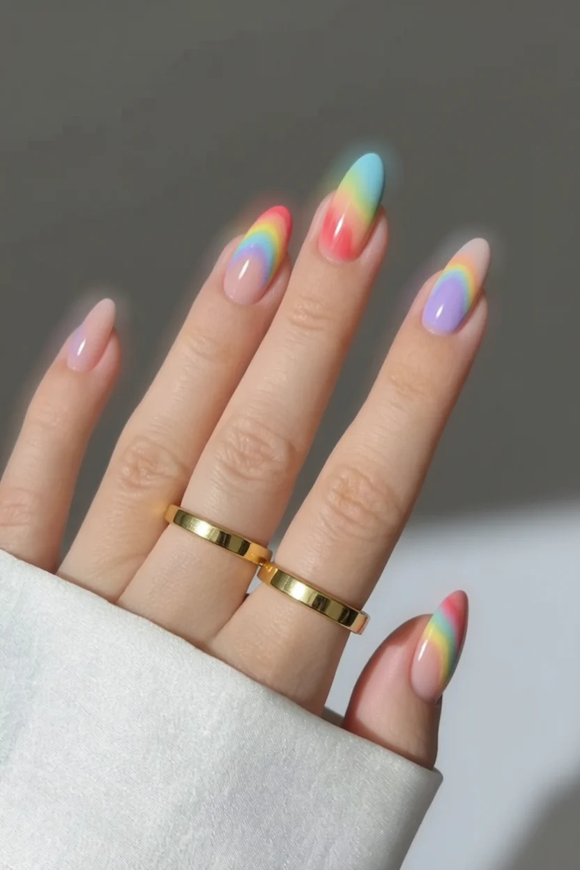 Mano con uñas almendradas degradado arcoíris pastel y puntas vibrantes
