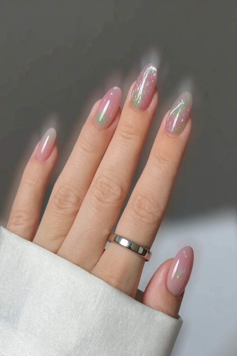 Uñas ovaladas con base rosa nude y delicados diseños florales blancos con hojas verdes