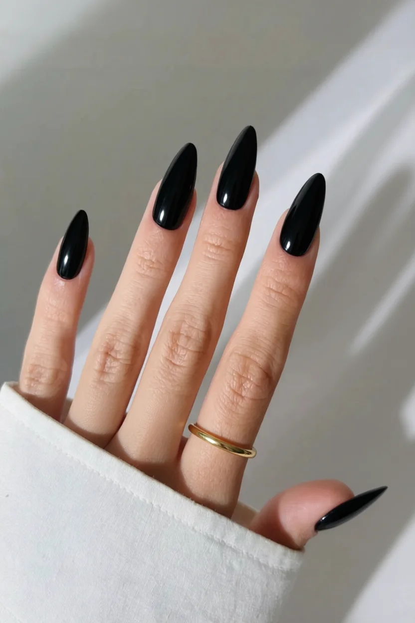 Uñas negras largas estilo stiletto con acabado brillante