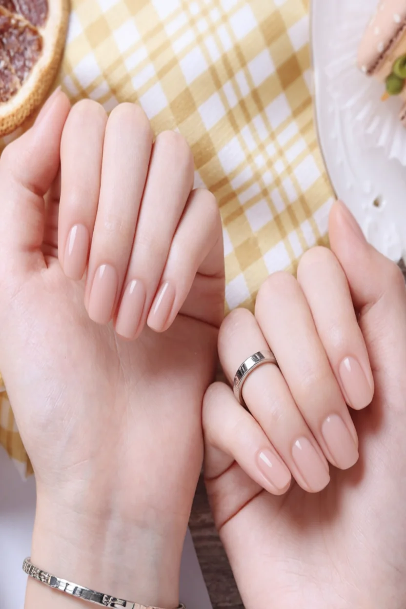 Manos con uñas cortas ovaladas en tono nude brillante y anillo de boda