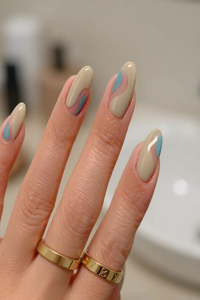 Uñas almendradas nude con diseño abstracto en azul y rosa pastel