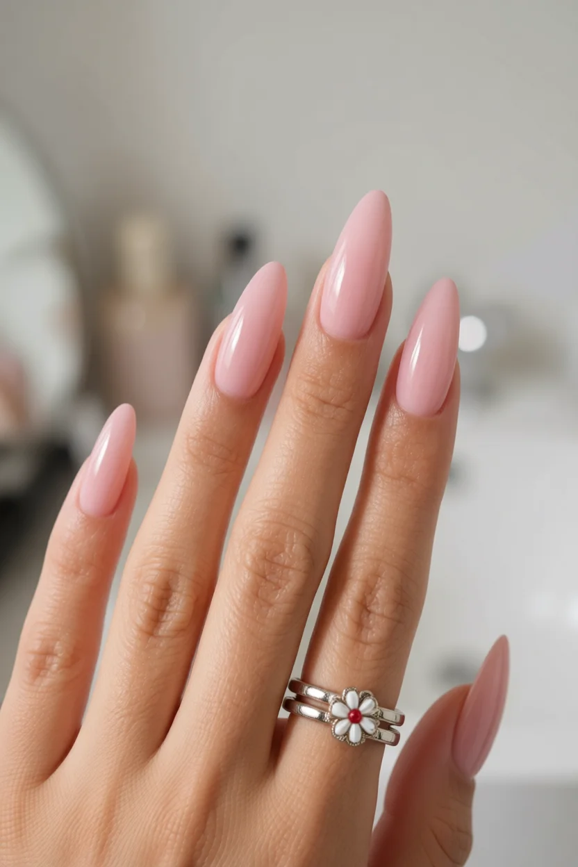 Mano con uñas largas en forma almendra y esmalte rosa pastel brillante