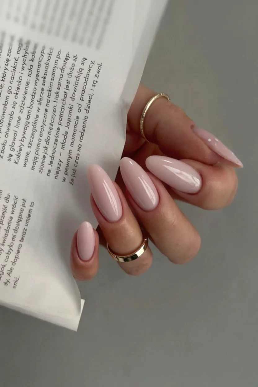 Mano con uñas almendradas largas en rosa pálido brillante y acabado gloss
