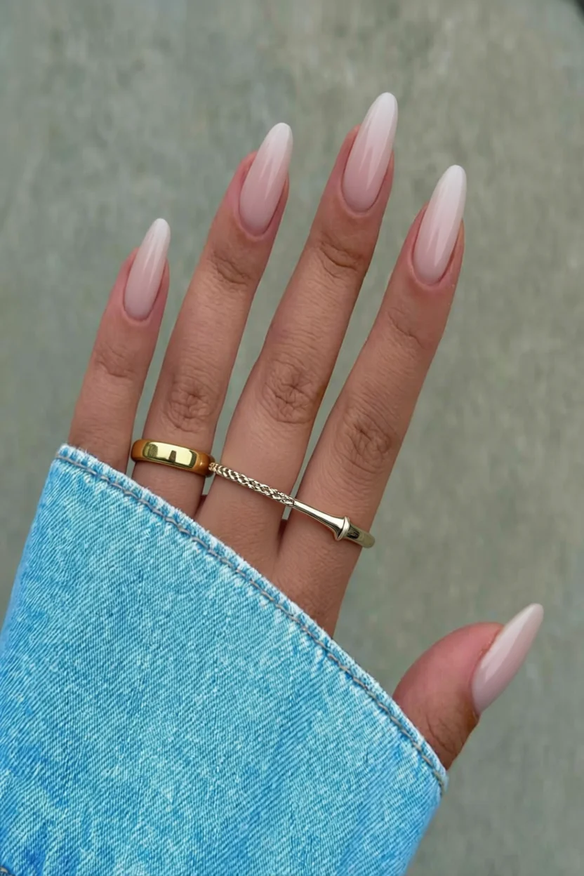 Mano con uñas largas almendradas en degradado rosa nude y brillo glossy