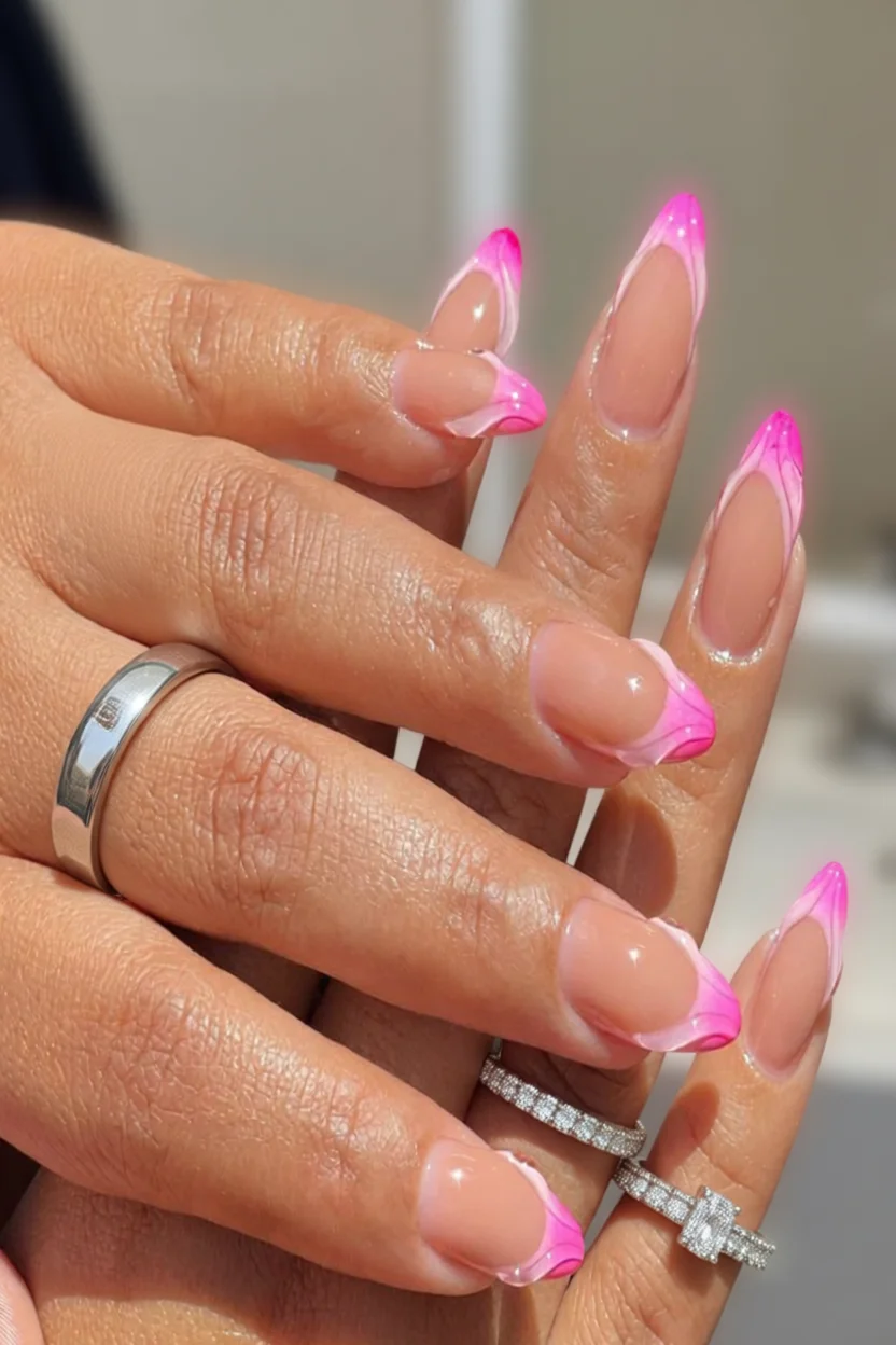 Uñas extralargas estilo stiletto con base nude y puntas degradadas en rosa fucsia brillante