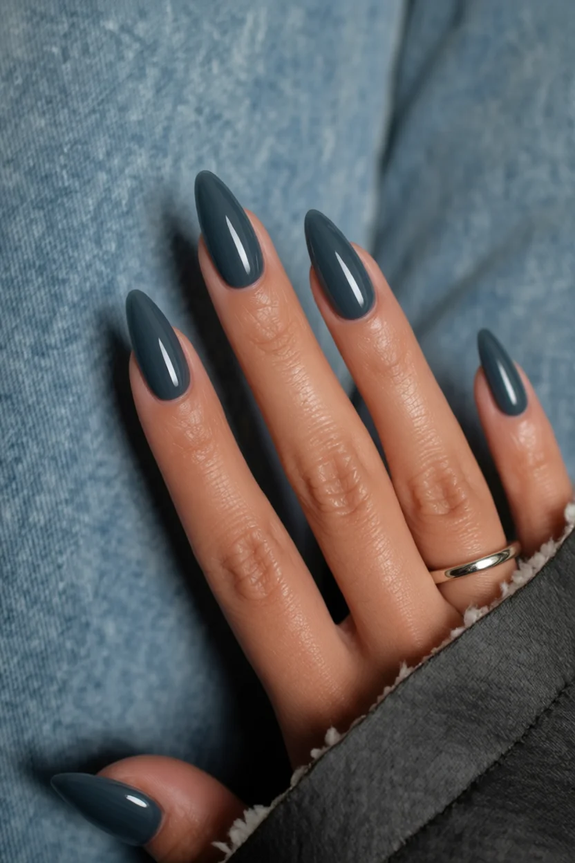 Mano con uñas largas en forma de almendra pintadas de azul acero sólido con brillo