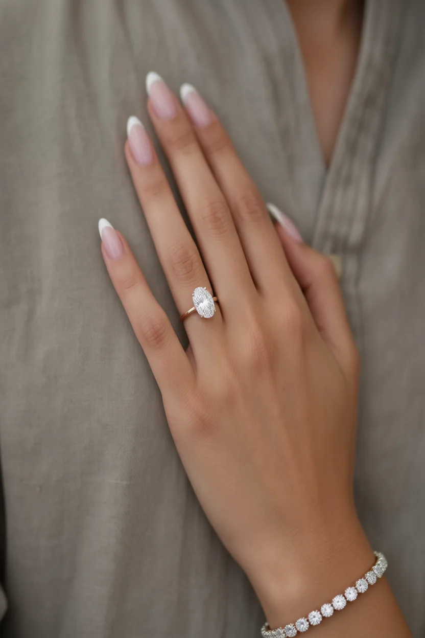 Mano con uñas francesas almendradas rosa y anillo de compromiso ovalado