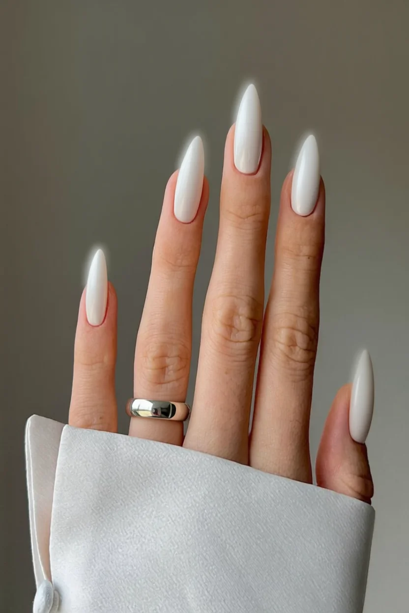 Mano con uñas largas blancas estilo stiletto mostrando anillo de compromiso