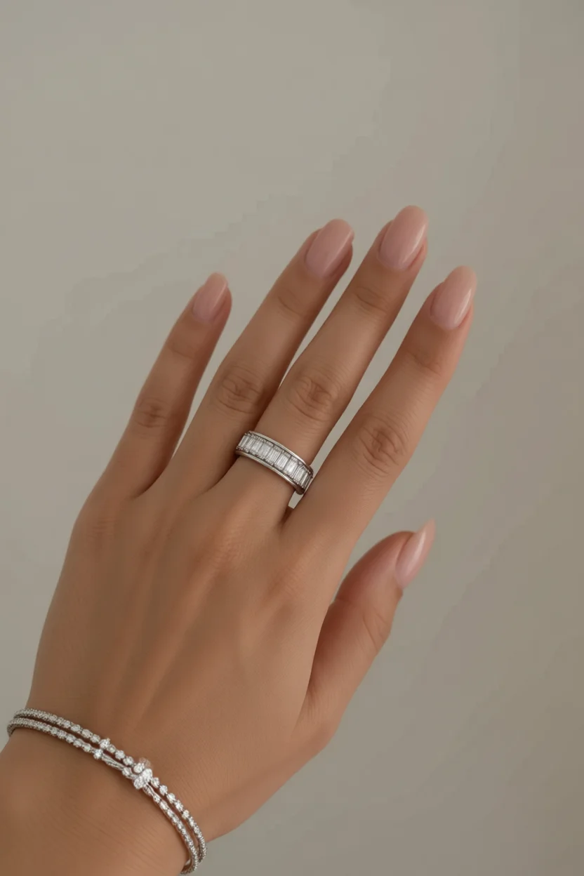 Mano con anillo de diamantes y uñas nude brillantes forma almendra