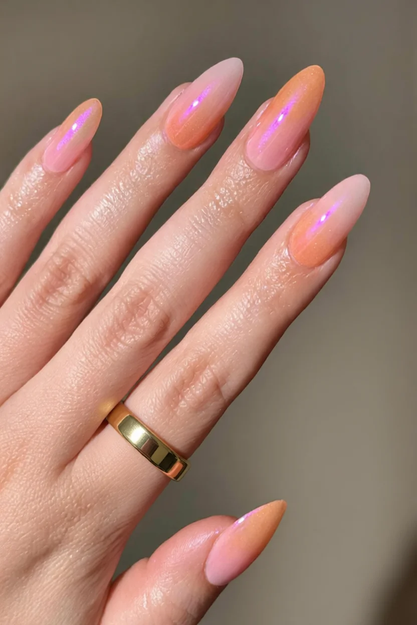 Mano con uñas almendradas en degradado rosa a naranja con efecto iridiscente holográfico