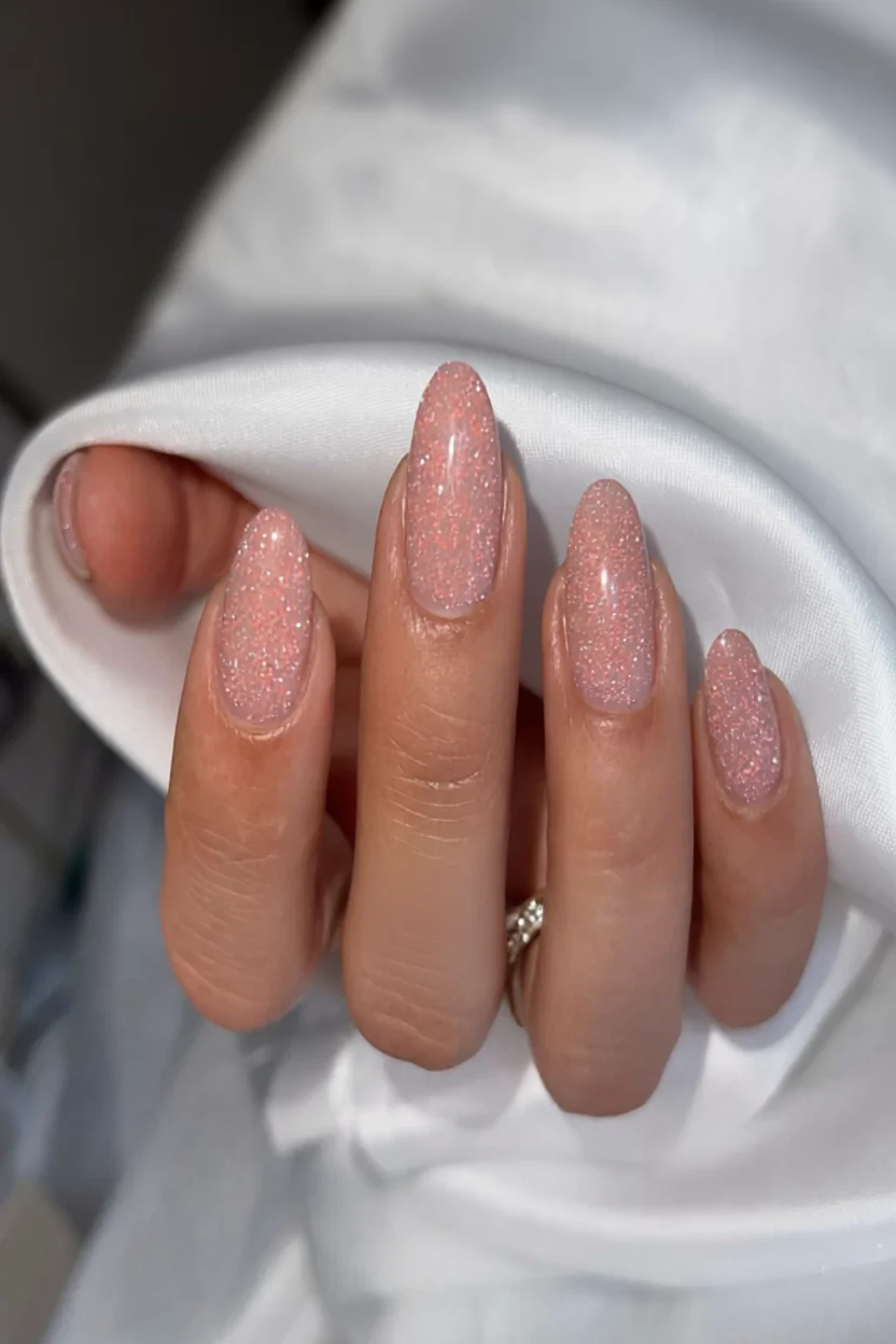 Uñas almendra con glitter rosa brillante y acabado luminoso