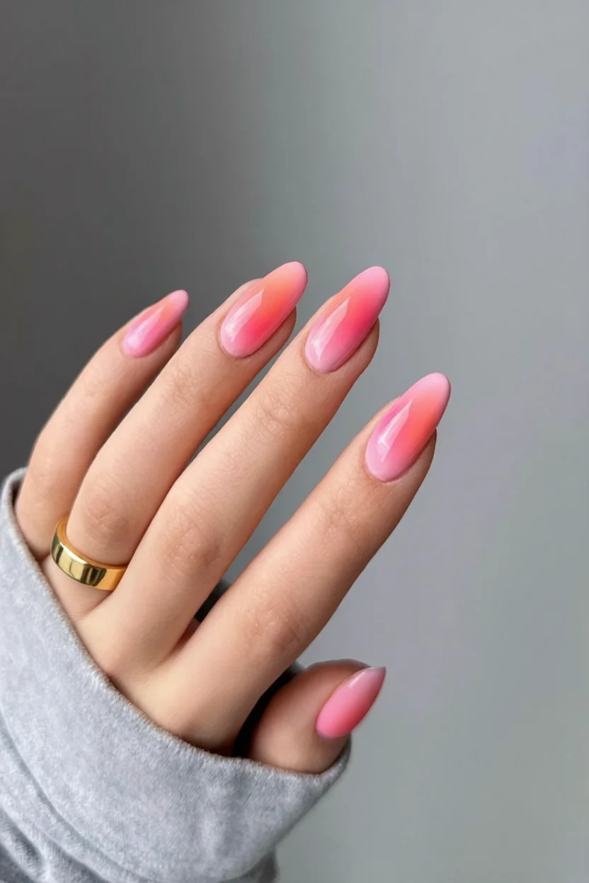 Mano con uñas largas forma almendra con efecto aura degradado de nude a rosa intenso