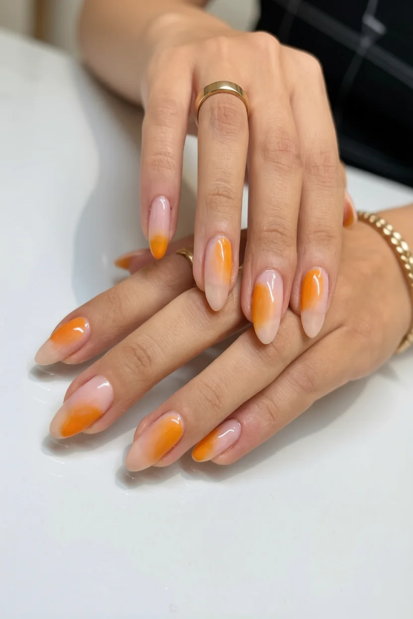 Mano con uñas ovaladas en efecto aura naranja degradado sobre base rosa