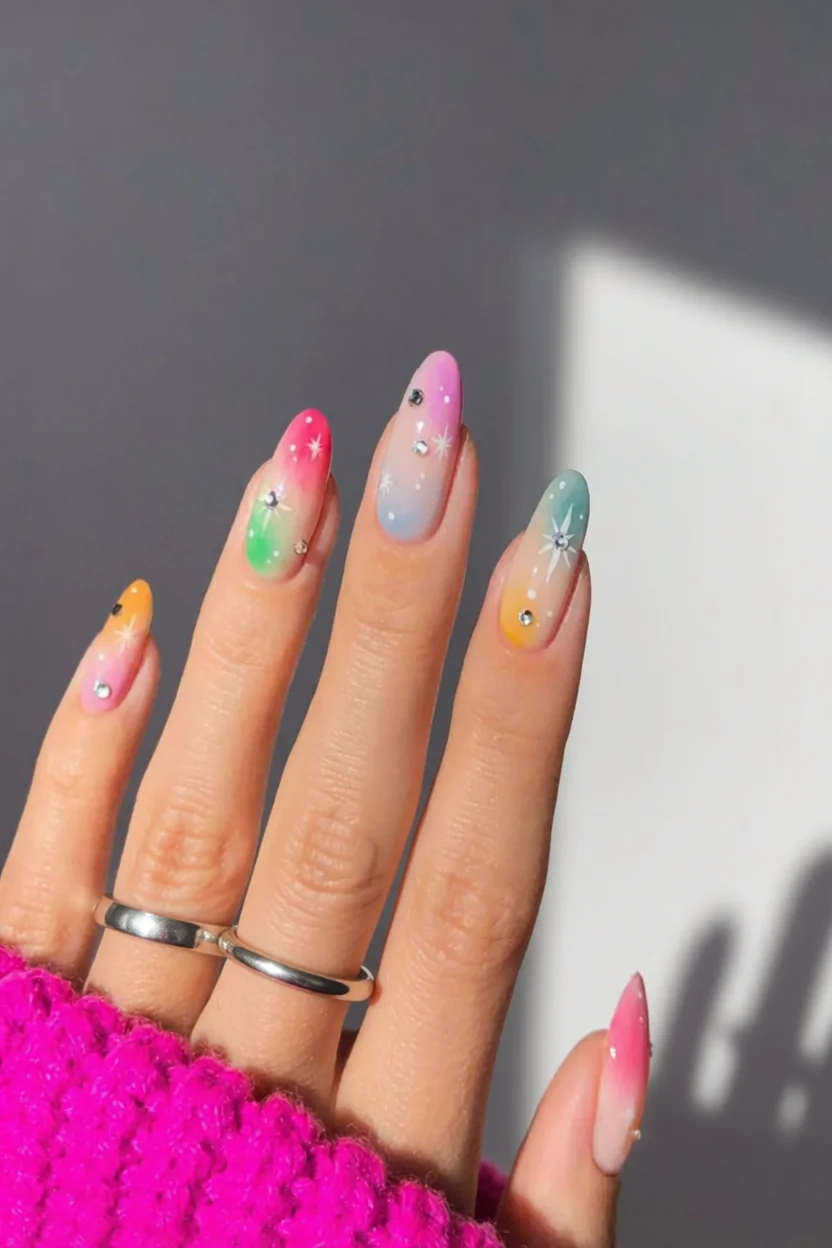 Uñas largas con efecto aura multicolor, estrellas pintadas y cristales decorativos