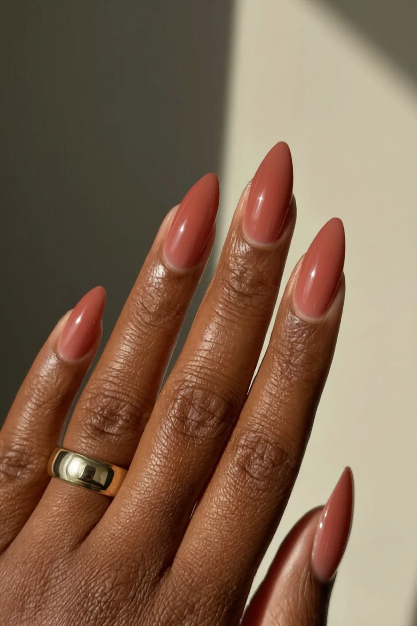 Uñas largas almendradas con efecto jelly translúcido en tono coral sobre piel oscura