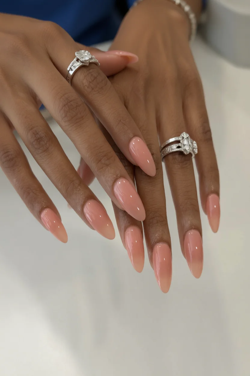 Mano con uñas largas en forma almendrada con efecto syrup degradado en tono melocotón rosa translúcido brillante