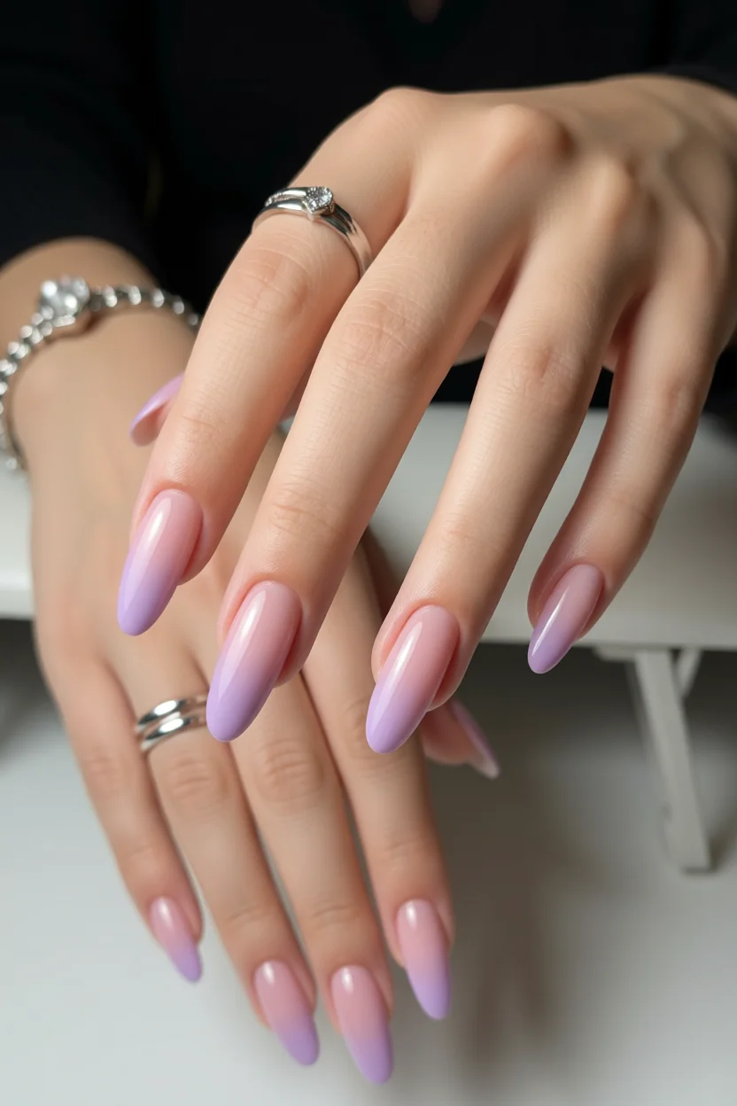 Mano con uñas largas ovaladas en efecto milky degradé rosa a lavanda