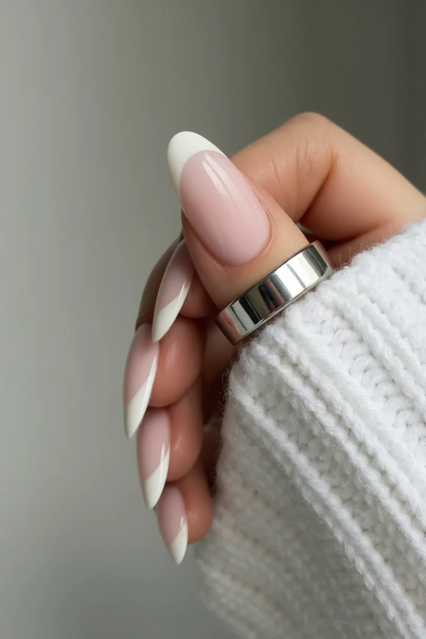 Mano con uñas largas almendradas efecto francés moderno rosa y blanco con suéter blanco
