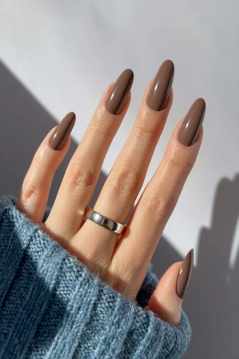 Uñas alargadas en forma almendrada con esmalte marrón chocolate brillante