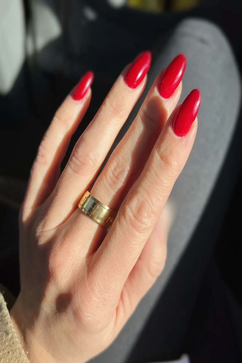 Mano con uñas largas en forma de almendra pintadas de rojo brillante