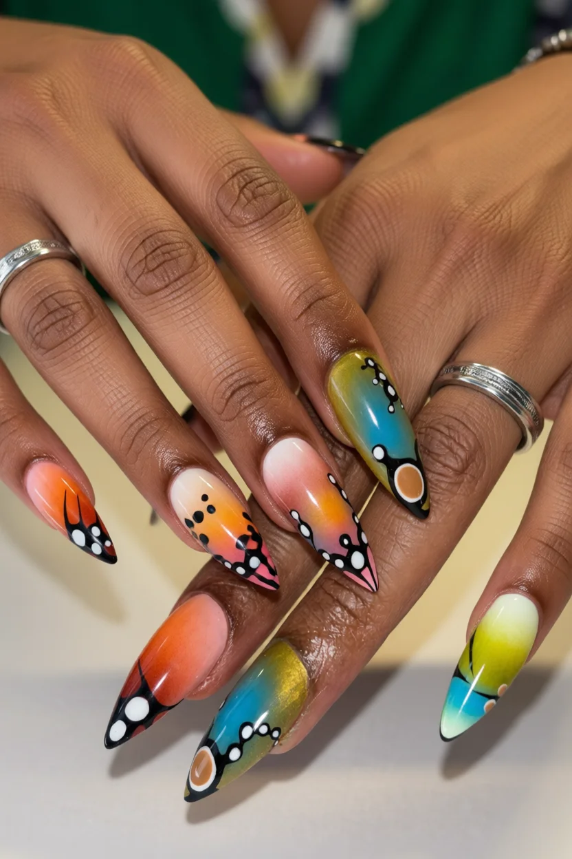 Uñas largas estiletó con degradado de colores vibrantes y detalles abstractos en negro
