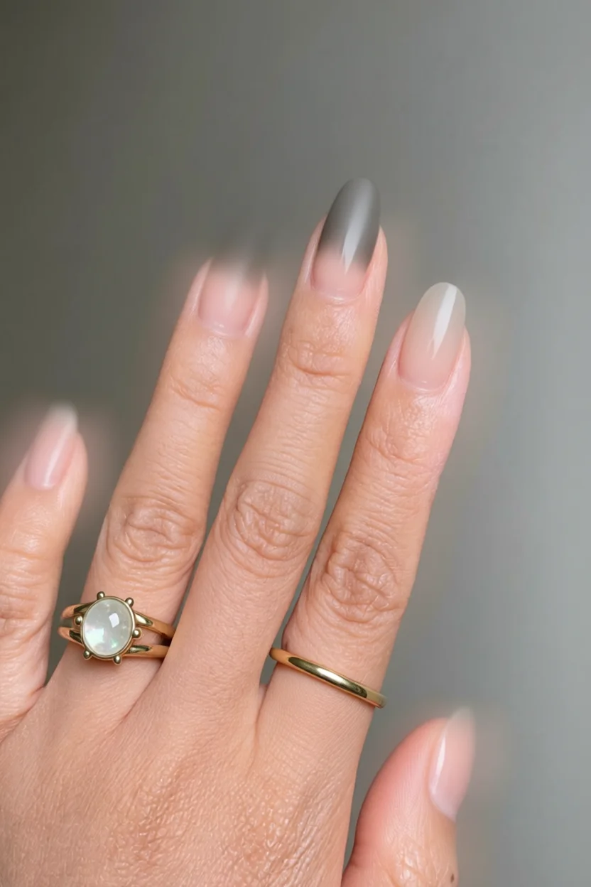 Mano con uñas largas ovaladas degradadas de nude a gris opaco