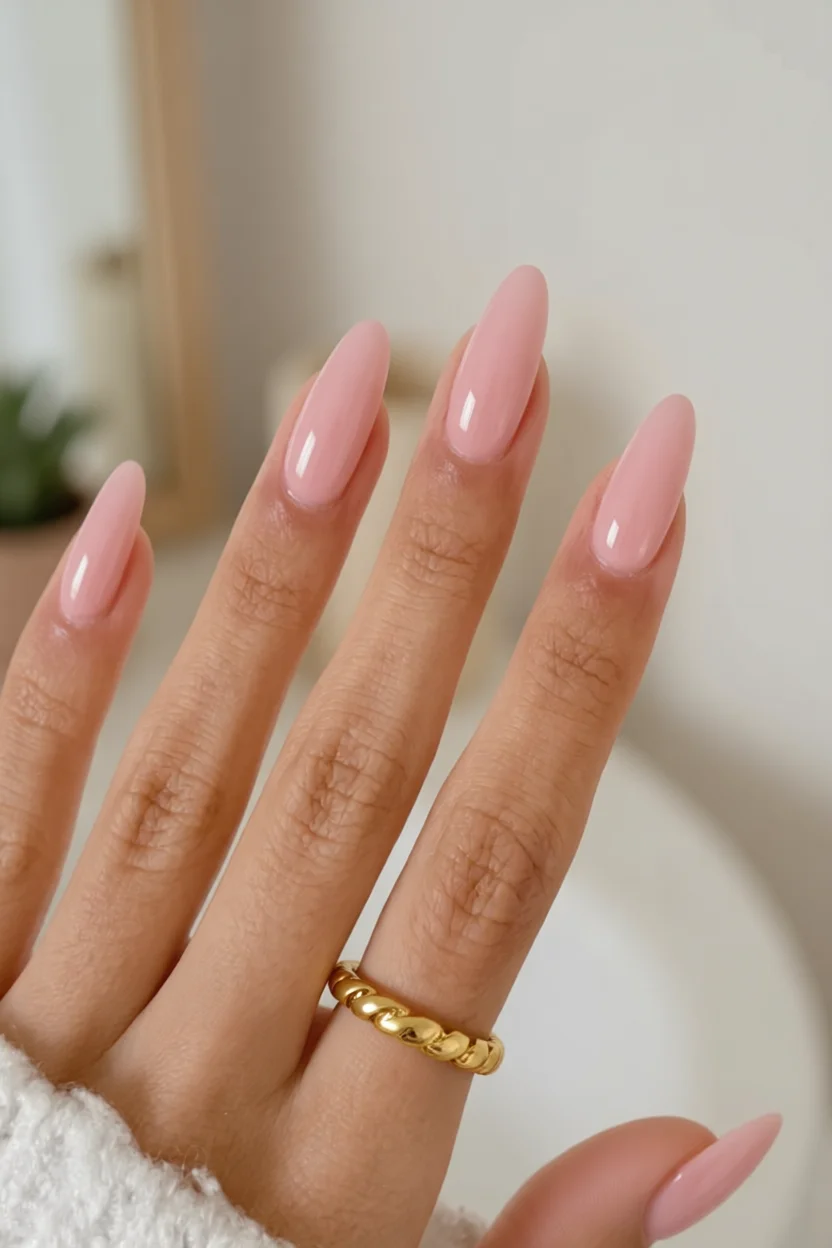 Mano con uñas largas en forma de almendra pintadas de color rosa suave con brillo glossy