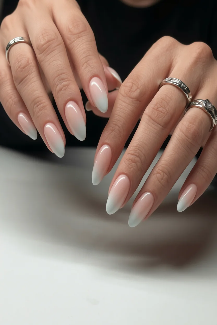 Mano con uñas largas en forma almendrada y efecto milky degradado de rosa suave a blanco