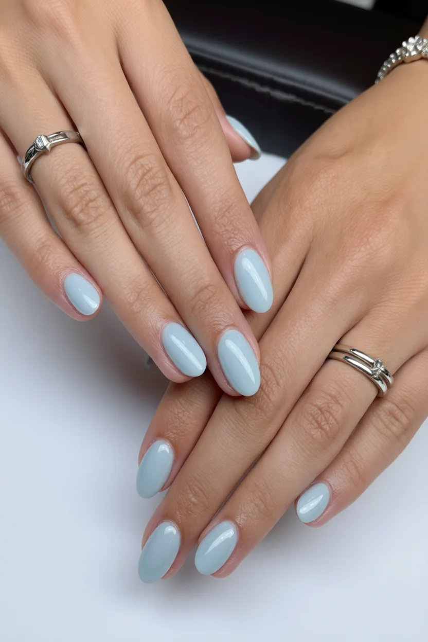 Manos con uñas almendradas esmaltadas en azul cielo translúcido efecto milky