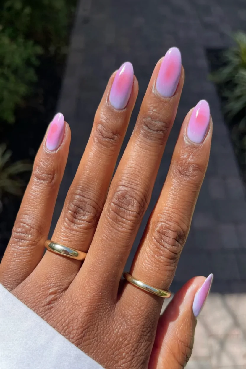 Mano con uñas cortas almendradas y efecto degradado rosa lila