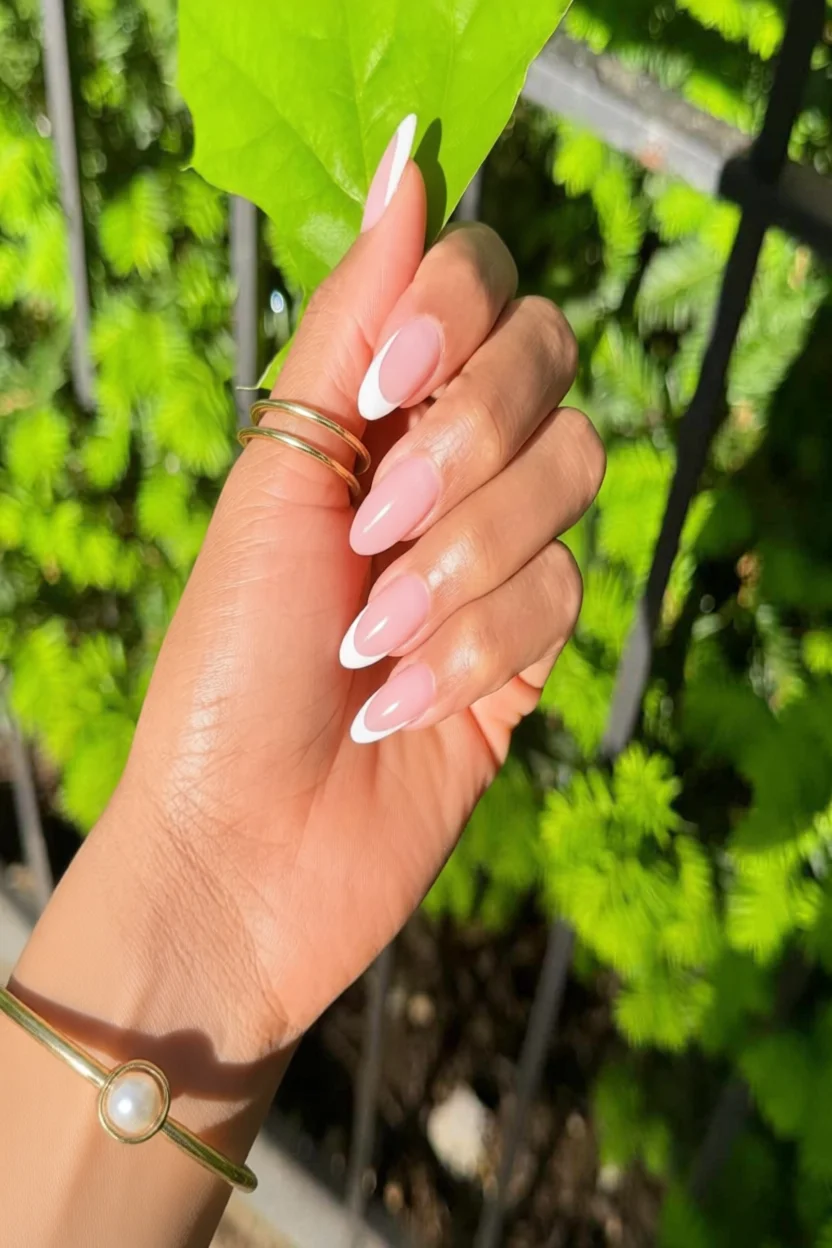 Mano con uñas almendradas color rosa pastel y puntas blancas estilo francés