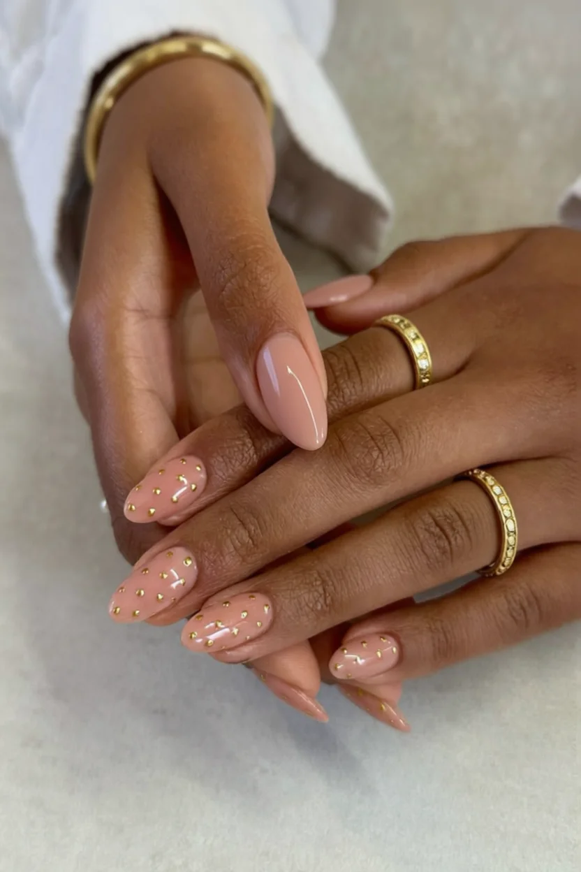 Uñas almendradas color nude con pequeños puntitos metálicos dorados