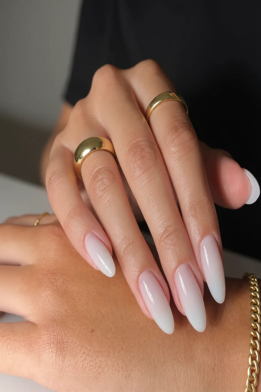Mano con uñas alien largas y puntiagudas en efecto degradado rosado a blanco brillante